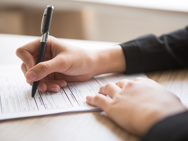 mains de femme remplissant un formulaire avec un stylo