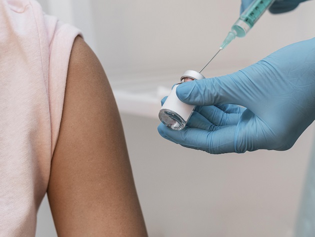 persnne tenant une sering de vaccin à côté d'un bras